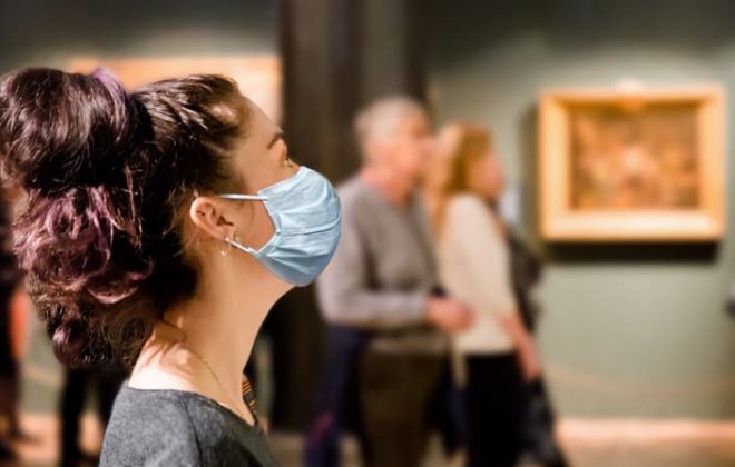 A patron wearing a mask while viewing work in a museum gallery
