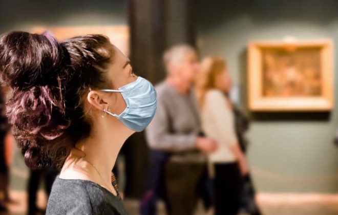 A patron wearing a mask while viewing work in a museum gallery