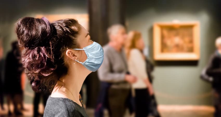 A patron wearing a mask while viewing work in a museum gallery