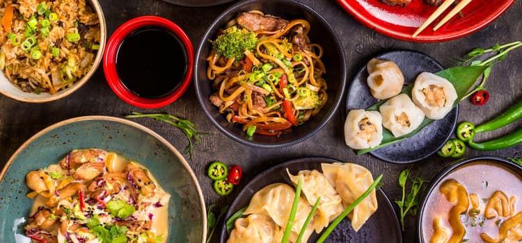 a table filled with dumplings, noodles, sauces, and vegetables