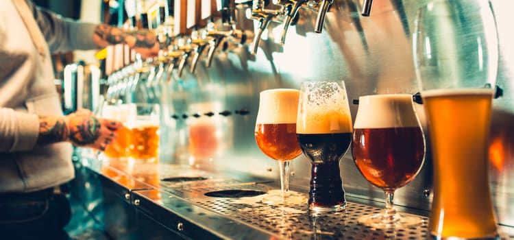 a row of glasses lined up under a beer tap