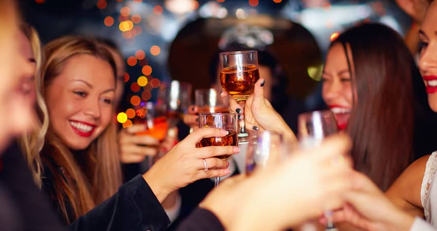 a group of women toasting drinks at a bar