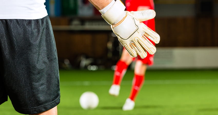 A goalie stands ready to defend a goal in an indoor soccer stadium