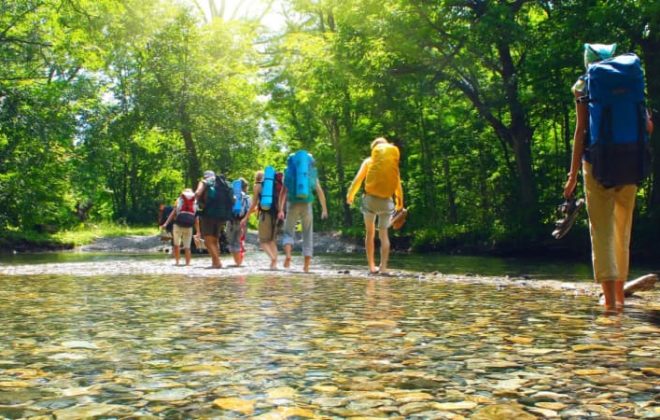 a group of hikers wading in a shallow river