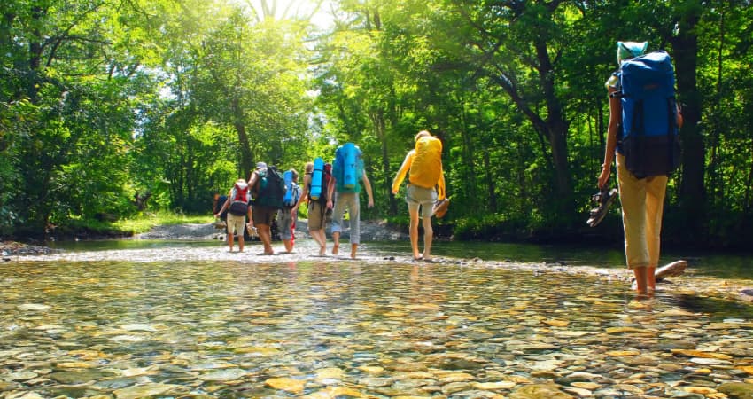 a group of hikers wading in a shallow river